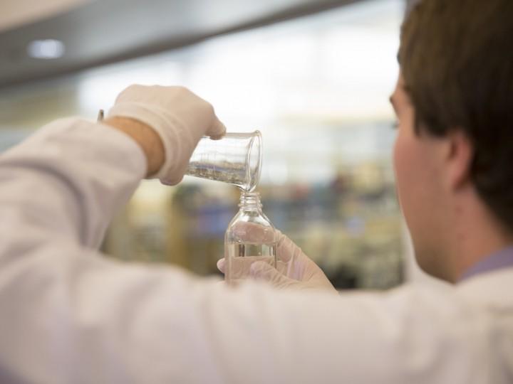 A student measuring wet compounding ingredient with graduated cylinder